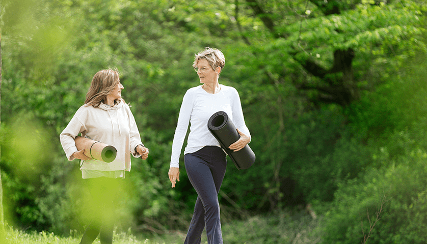 Zwei Frauen laufen mit Yogamatte durch den Park