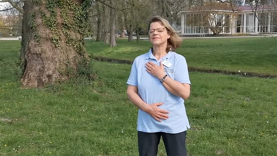 Frau zeigt Atemübung im Park